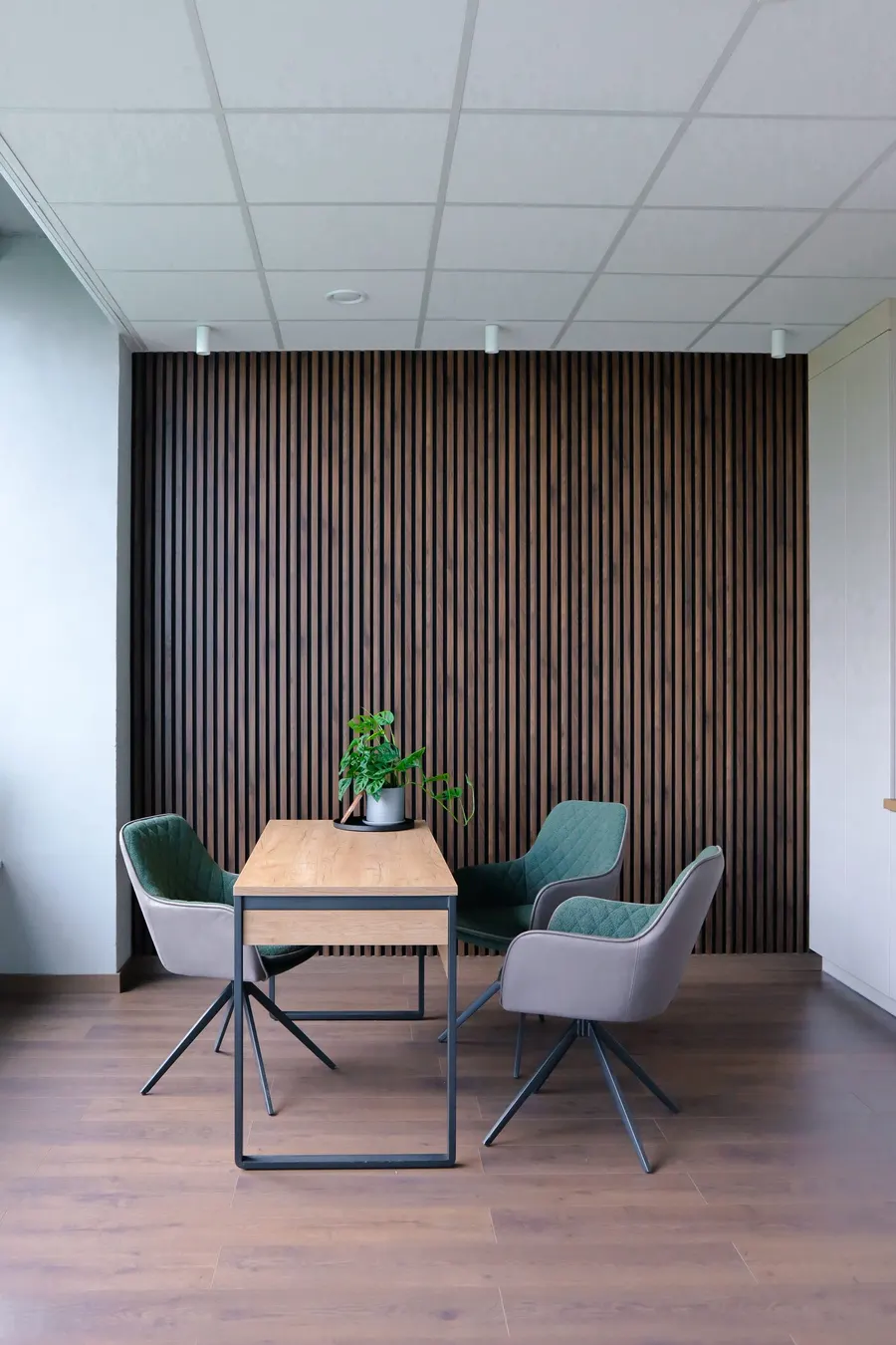 Strefa konsultacji — drewniane panele lamelowe i nowoczesne krzesła