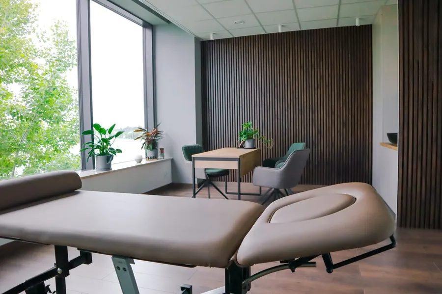 Gabinet osteopatii — stół terapeutyczny i strefa konsultacji z panelami drewnianymi